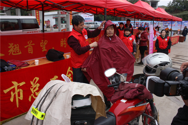 梧州市總工會的黨員義工們在市東出口春運服務站助力&ldquo;摩托大軍&rdquo;平安返鄉(xiāng)，幫助他們檢查車輛和行李，穿上雨衣。--黃賀峰攝.j